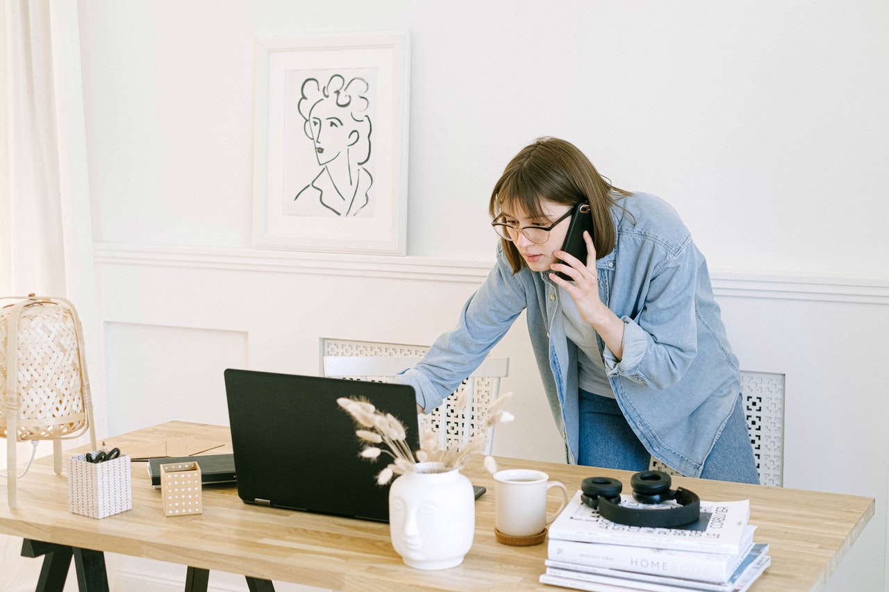 woman on phone, pointing at her laptop